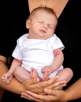 Newborn baby held in his mother's arms