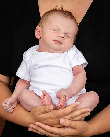 Newborn baby held in his mother's arms