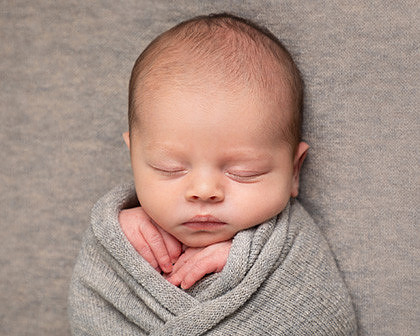 Newborn baby swaddled in grey - a studio photograph by Windsor photographer, Abi Moore