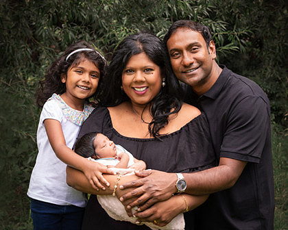 Newborn baby cradled in his mother's arms with father and sister eitherside, photographed outdoors