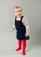 Toddler girl stands in a photo studio laughing