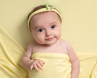 Baby lays on a yellow blanket covered in yellow with a yellow headband