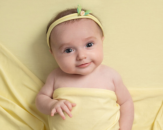 Baby lays on a yellow blanket covered in yellow with a yellow headband