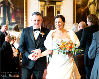 A bride and groom smile broadly as they walk out of their ceremony at Windsor Guildhall