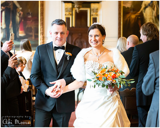 A bride and groom smile broadly as they walk out of their ceremony at Windsor Guildhall