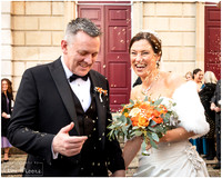 Bride and groom laugh as they are showered with confetti