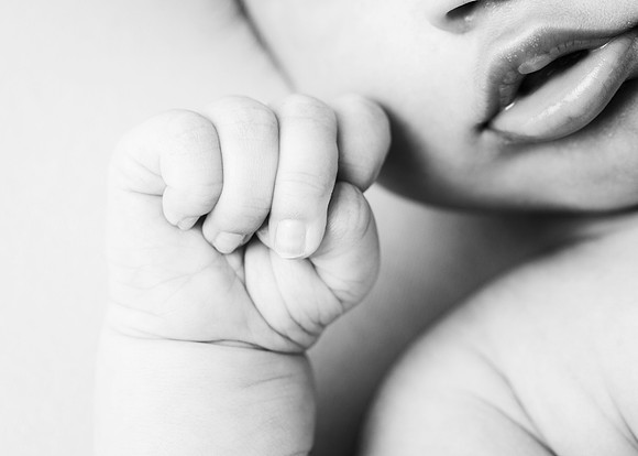 Black & white close up of newborn baby's hand and lips