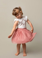 Three-year-old girls spins in a photo studio setting wearing a pink tutu and sparkly top