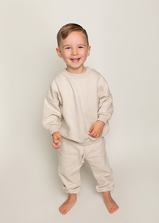 Boy standing dresed in cream photographed on a cream backdrop