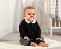 A baby sits on a rug modelling baby wear for a catalogue photoshoot