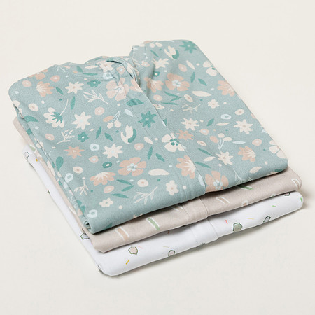 Three baby sleep sacks folded into squares and stacked on a studio backdrop