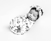 Newborn baby wrapped in a floral wrap and headband photographed in black & white