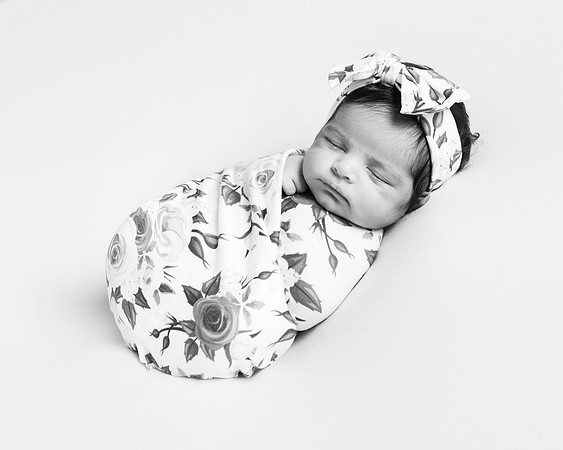 Newborn baby wrapped in a floral wrap and headband photographed in black & white