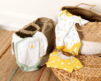 Three baby vests arranged over wicker baskets