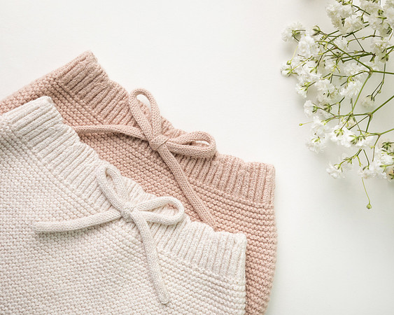 Two pairs of knitted bloomers photographed on a studio background dressed with gypsophila