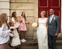 A wedding couple smile as their daughters shower them with confetti