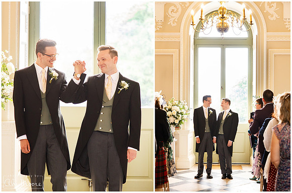 Two grooms raise hands together at the end of their wedding ceremony