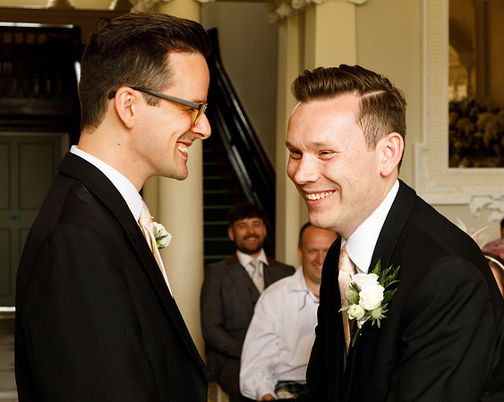 Two grooms laugh during their wedding ceremony