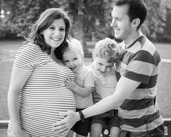 Family smile and embrace; hands touching mum's baby bump