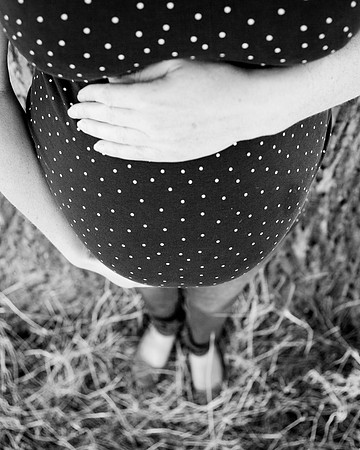 Mum cradles baby bump outdoors photographed from above