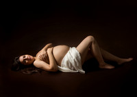 Studio photo of expectant mother laying on her back