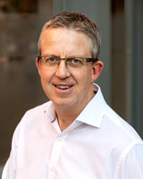A professional headshot of a man outside an office