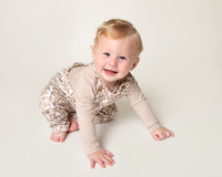 Baby crawling and smiling at the camera, photographed in a studio