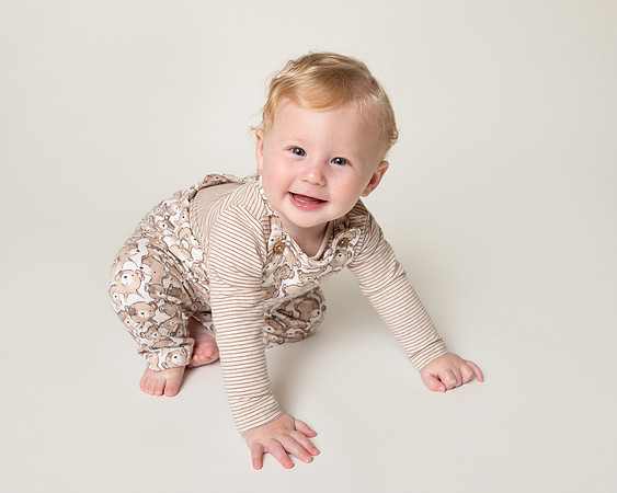 Baby crawling and smiling at the camera, photographed in a studio
