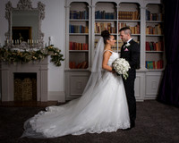 A wedding couple look at each other in the Berystede's library, the brides dress and train are very long