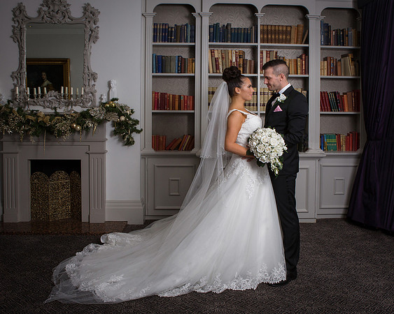 A wedding couple look at each other in the Berystede's library, the brides dress and train are very long