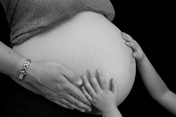 Close-up photo of child's hands on mum's baby bump