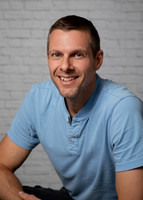 A man smiles at the camera in a relaxed headshot