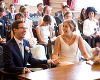 A wedding couple giggle surrounded by their guests inside the Windsor Guildhall