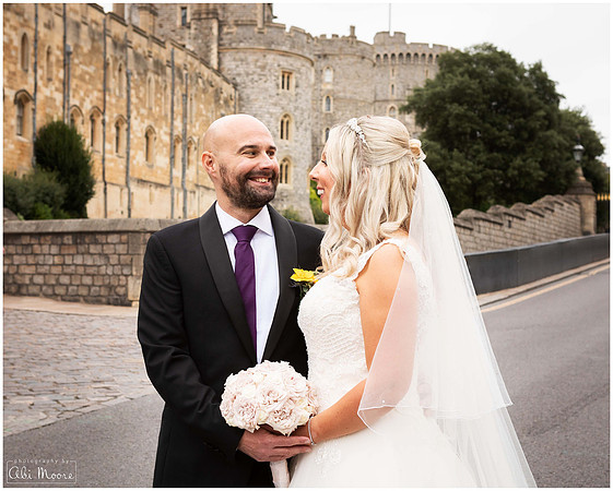 A bride and groom smile at each other outside Windsor Castle