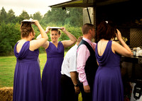 A bridesmaid makes a face whilst queueing for food and sheltering from the rain with a plate over her head