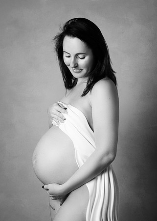 Pregnant mother posing undressed with a white cloth draped across her