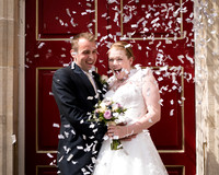 A bride and groom laugh as they are showered with confetti outside Windsor Guildhall