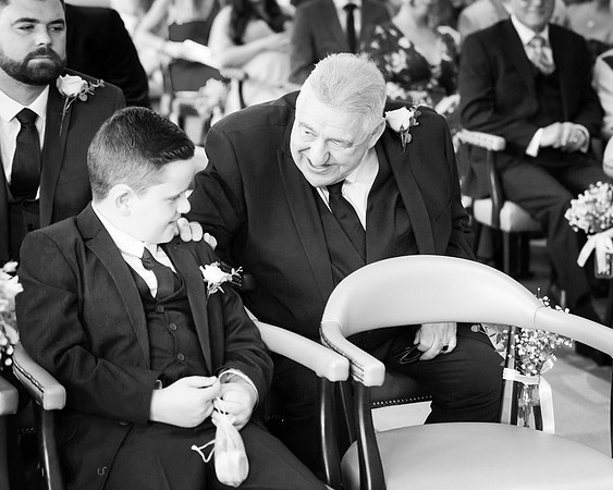 A grandfather comforts his grandson who is the ring bearer at his parents’ wedding