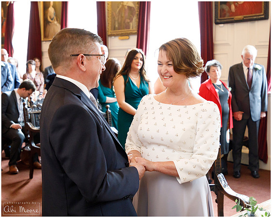 Bride & groom smile at each other as they hold hands and say their wedding vows at Windsor Guildhall