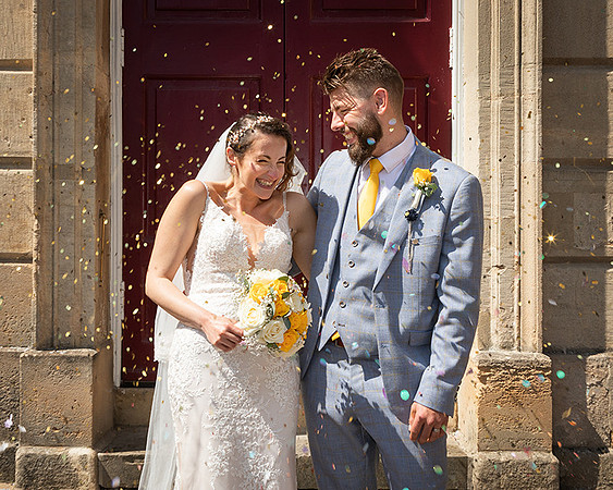 Bride and groom laugh as they are showered with confetti outside the Windsor Guildhall