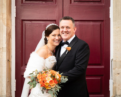 A bride and groom smile naturally outside the doors of Windsor Guildhall