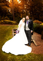 A bride & groom smile at the camera in Autumn light in the Berystede's gardens