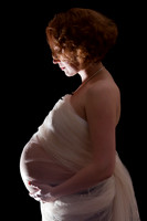 Woman back lit with baby bump wrapped in organza