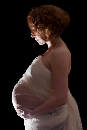 Woman back lit with baby bump wrapped in organza