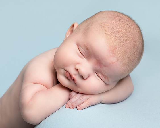 Baby fast asleep gently posed resting his head on his hands