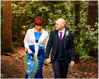 Relaxed photo of bride and groom walking in woodland on their wedding day