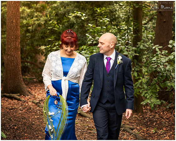 Relaxed photo of bride and groom walking in woodland on their wedding day