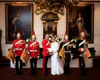 A wedding couple stand in Windsor Guildhall's Grand Chamber flanked by military trumpeteers (groom is also in military uniform)