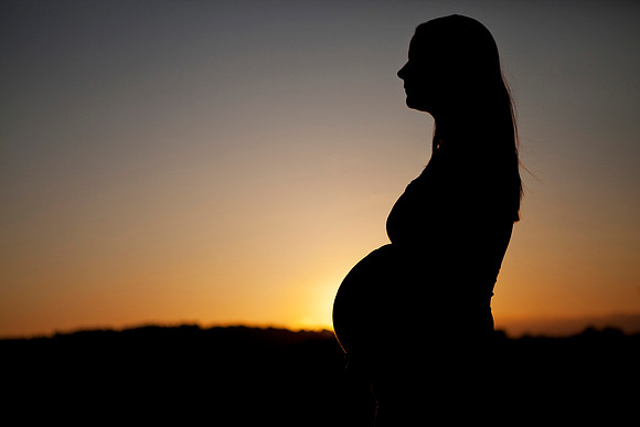 Silhouette of pregnant mother at sunset