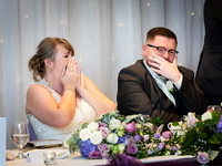 Wedding couple laugh and cover their faces during the best man's speech